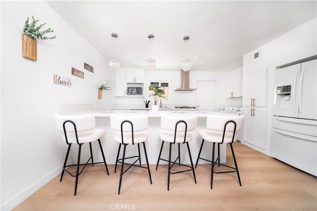 10091011 W Myrtle St, Santa Ana, CA 92703 - kitchen with white fridge with ice dispenser, wall chimney range hood, a breakfast bar, and white cabinets