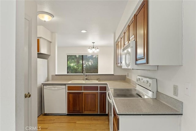 2912 Pennyroyal Dr, Chico, CA 95928 - kitchen with white appliances, a sink, brown cabinets, a chandelier, and light wood-style flooring