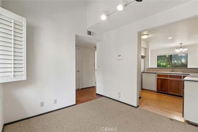 2912 Pennyroyal Dr, Chico, CA 95928 - kitchen with white dishwasher, a sink, light carpet, brown cabinetry, and a chandelier