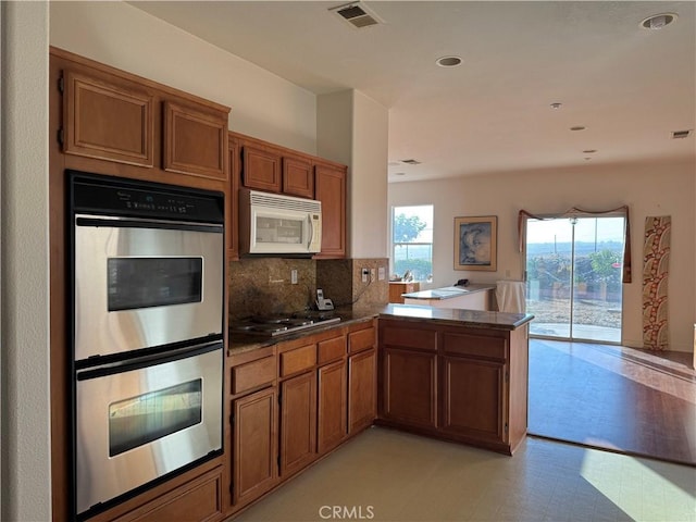 5486 Alexandrine Ct, Oceanside, CA 92057 - kitchen with white microwave, double oven, gas cooktop, a peninsula, and brown cabinetry