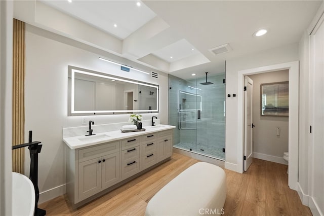 full bath with a stall shower, baseboards, wood finished floors, toilet, and double vanity