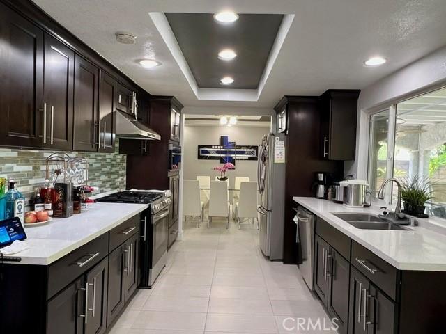 2163 N Justin Ave N, Simi Valley, CA 93065 - kitchen featuring appliances with stainless steel finishes, a sink, tasteful backsplash, under cabinet range hood, and light countertops