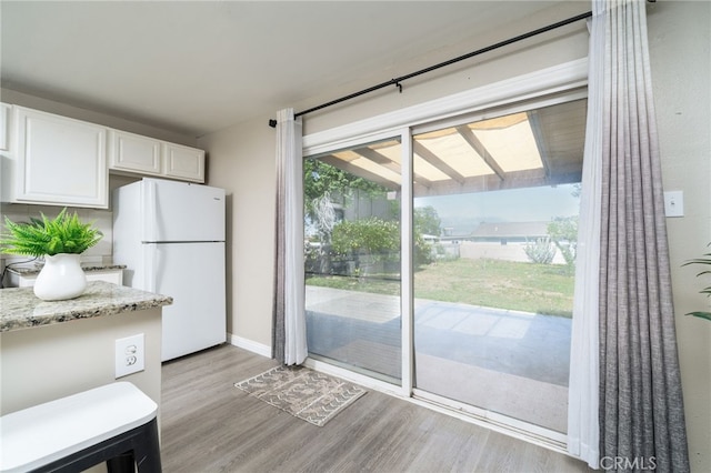 1963 Turrill Ave, San Bernardino, CA 92411 - kitchen featuring freestanding refrigerator, light wood-type flooring, white cabinets, and light stone countertops
