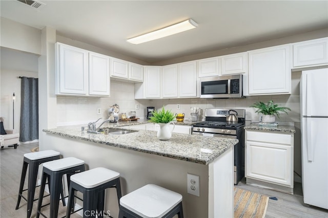 1963 Turrill Ave, San Bernardino, CA 92411 - kitchen with stainless steel appliances, white cabinetry, a kitchen bar, and decorative backsplash