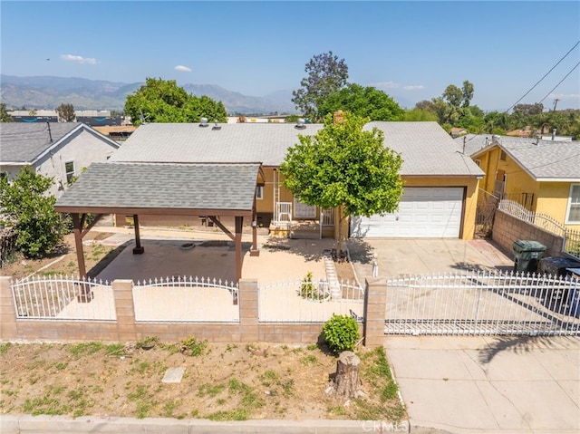 1963 Turrill Ave, San Bernardino, CA 92411 - view of front facade featuring concrete driveway, a fenced front yard, roof with shingles, a garage, and a mountain view