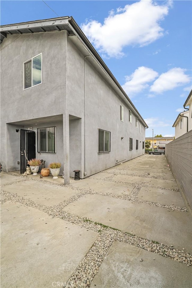 202 E 116th St, Los Angeles, CA 90061 - rear view of house featuring stucco siding, fence, and a patio area