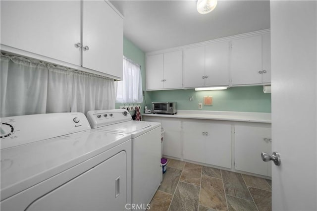washroom with washer and dryer, stone finish flooring, and cabinet space
