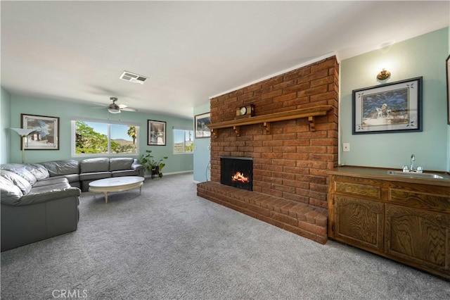 living area featuring carpet, a brick fireplace, and a ceiling fan