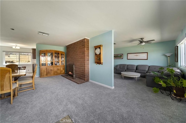 living area featuring carpet floors, a brick fireplace, ceiling fan, and baseboards
