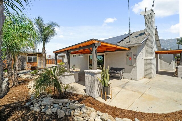 8631 Holly St, Rancho Cucamonga, CA 91701 - back of house featuring a patio, roof mounted solar panels, outdoor lounge area, stucco siding, and a chimney