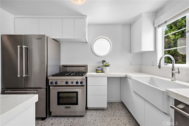 2142 Ruby Pl, Laguna Beach, CA 92651 - kitchen featuring high quality appliances, dark aggregate flooring, a sink, and white cabinetry