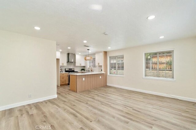 1988 Thornton St, Riverside, CA 92507 - kitchen featuring open floor plan, wall chimney range hood, recessed lighting, light countertops, and a peninsula