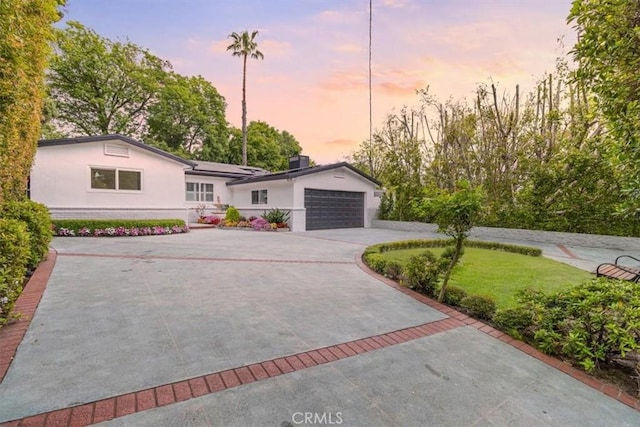 12535 Kling St, Studio City, CA 91604 - ranch-style house featuring curved driveway, stucco siding, solar panels, a garage, and a lawn