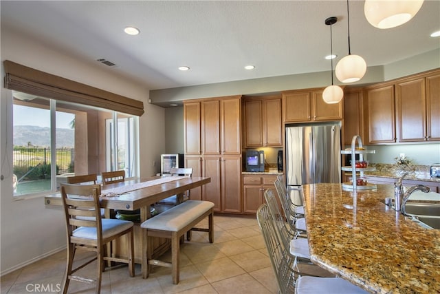 84692 Pavone Way, Indio, CA 92203 - kitchen with a sink, freestanding refrigerator, brown cabinetry, recessed lighting, and light tile patterned floors