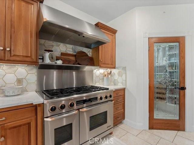 25179 68th Ave, Los Molinos, CA 96055 - kitchen with range with two ovens, wall chimney exhaust hood, brown cabinets, light countertops, and light tile patterned flooring