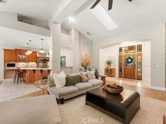 25179 68th Ave, Los Molinos, CA 96055 - living room featuring high vaulted ceiling, arched walkways, ceiling fan, a skylight, and baseboards