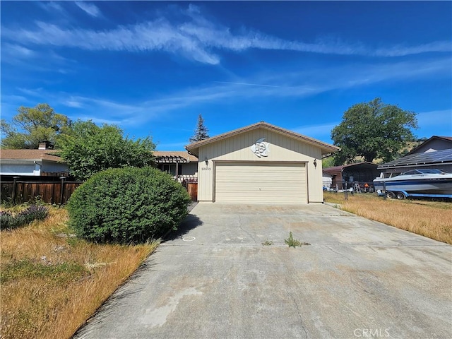 view of front of home featuring fence, concrete driveway, and an attached garage