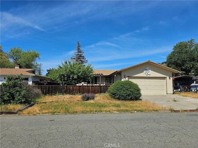 view of front of property with fence, an attached garage, and concrete driveway