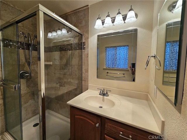 bathroom with a stall shower, vanity, and a textured wall