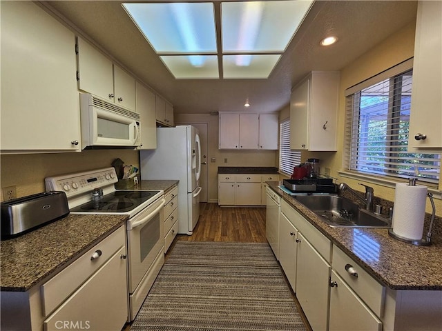 kitchen featuring white appliances, a sink, dark wood-type flooring, white cabinets, and dark countertops