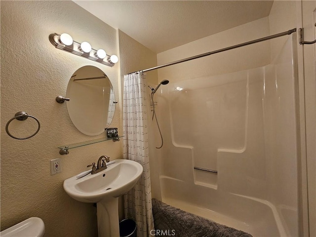 full bath featuring a shower with curtain, a textured wall, and toilet