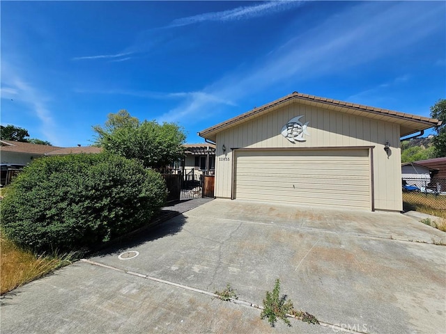 garage featuring fence, concrete driveway, and a gate