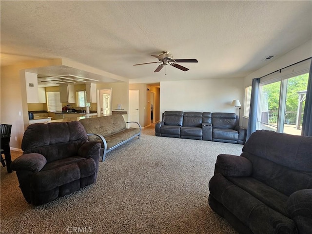 living area with carpet floors, ceiling fan, a textured ceiling, and baseboards