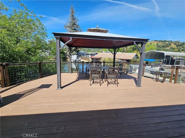 wooden deck with a gazebo, a detached carport, and outdoor dining space