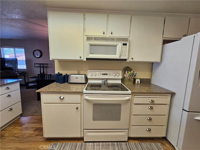 kitchen with white appliances, dark wood finished floors, a textured ceiling, and white cabinetry