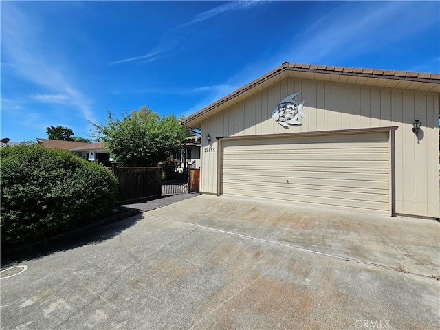 garage featuring concrete driveway and fence