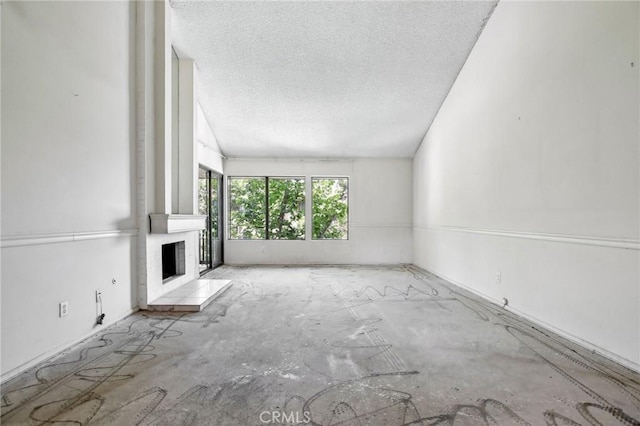 2506 E Willow St Unit 302, Signal Hill, CA 90755 - unfurnished living room featuring a textured ceiling, a brick fireplace, and vaulted ceiling