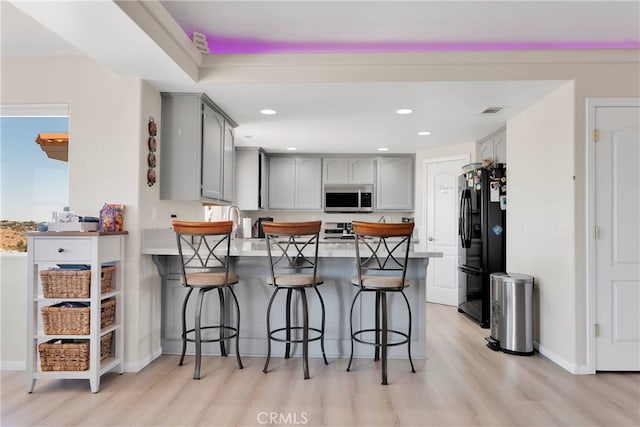7138 Amanda Way, Hesperia, CA 92345 - kitchen featuring stainless steel microwave, freestanding refrigerator, a peninsula, gray cabinetry, and light wood finished floors