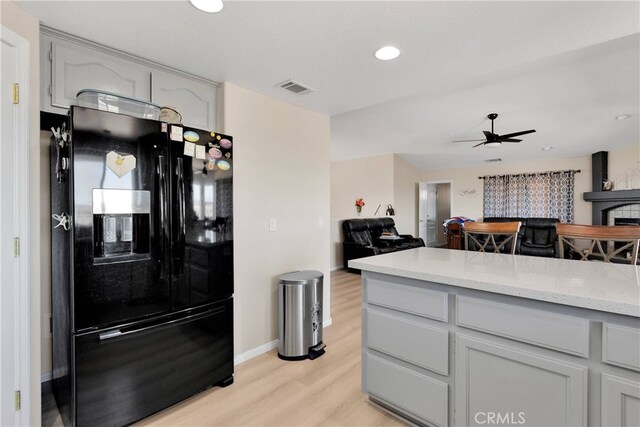 7138 Amanda Way, Hesperia, CA 92345 - kitchen with black refrigerator with ice dispenser, light wood-type flooring, ceiling fan, open floor plan, and a fireplace