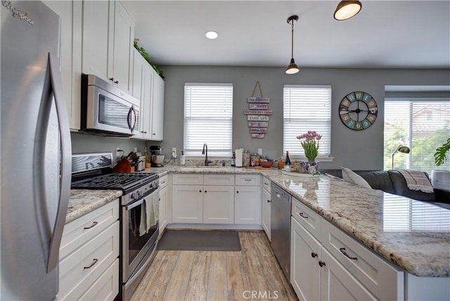 594 Rockaway Ave Unit B, Grover Beach, CA 93433 - kitchen with stainless steel appliances, a sink, a peninsula, white cabinets, and light wood-style floors