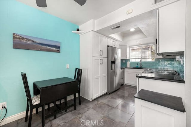 23391 La Crescenta Unit 270C, Mission Viejo, CA 92691 - kitchen featuring stainless steel refrigerator with ice dispenser, dark countertops, a raised ceiling, white cabinetry, and decorative backsplash