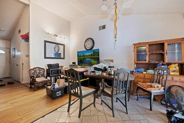 435 Leverett Ave, La Puente, CA 91744 - dining room featuring a textured ceiling, light wood-type flooring, and high vaulted ceiling