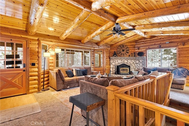 carpeted living area with rustic walls, wooden ceiling, a ceiling fan, and a stone fireplace