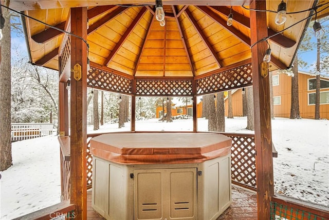 snow covered patio featuring a hot tub, a gazebo, and fence