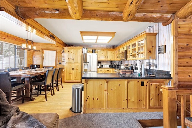 kitchen with stainless steel fridge, dark countertops, a peninsula, range, and beamed ceiling
