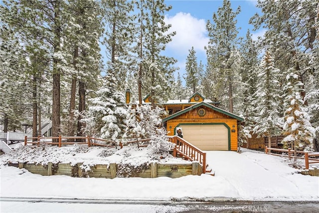 chalet / cabin featuring a garage and fence