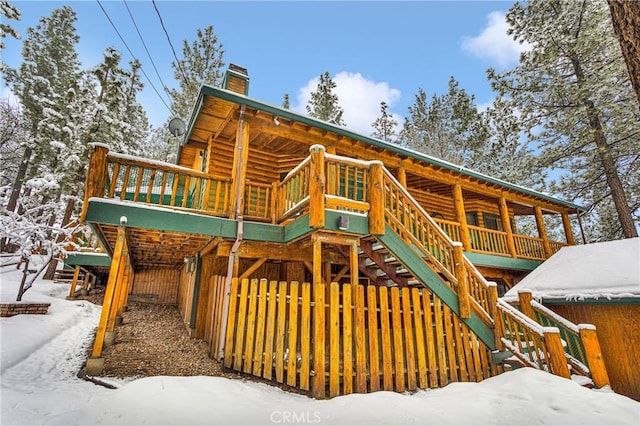 snow covered property featuring a chimney and stairway