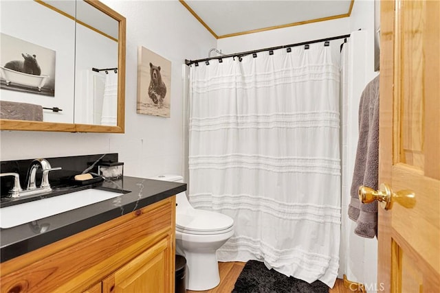 bathroom with toilet, vanity, wood finished floors, ornamental molding, and curtained shower