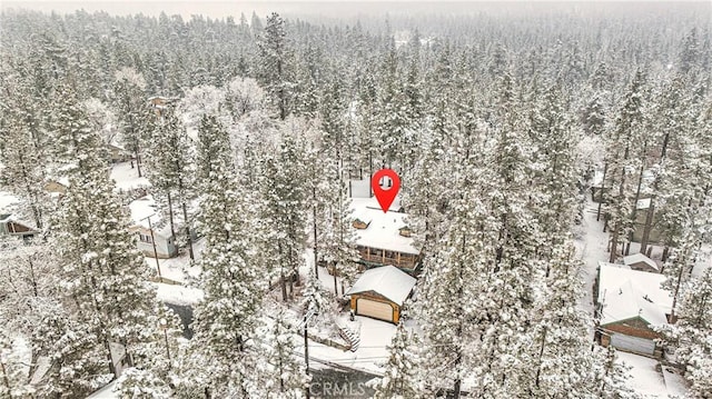 snowy aerial view featuring a wooded view