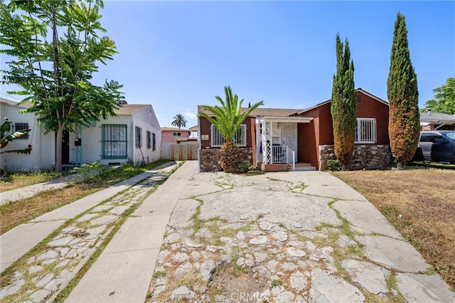 1022 W 101st St, Los Angeles, CA 90044 - view of front of home featuring stone siding, concrete driveway, stucco siding, and covered porch