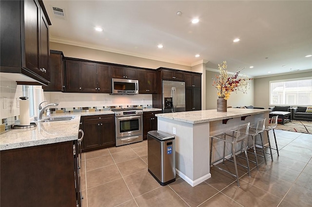 2303 Jefferson St Unit 1215, Torrance, CA 90501 - kitchen with appliances with stainless steel finishes, a sink, ornamental molding, light tile patterned floors, and a center island