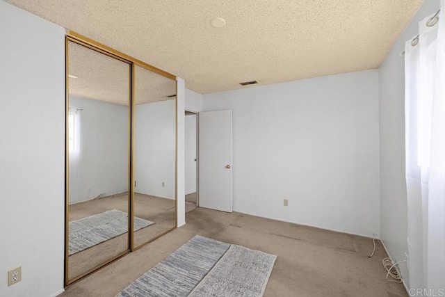 unfurnished bedroom with a textured ceiling, carpet floors, and a closet