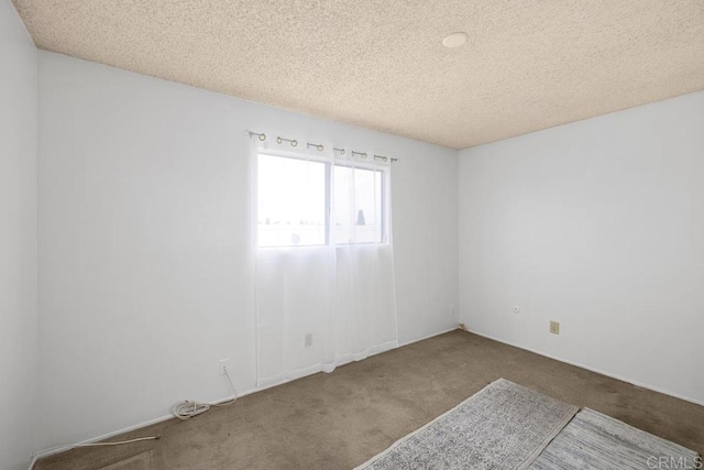 carpeted empty room featuring a textured ceiling