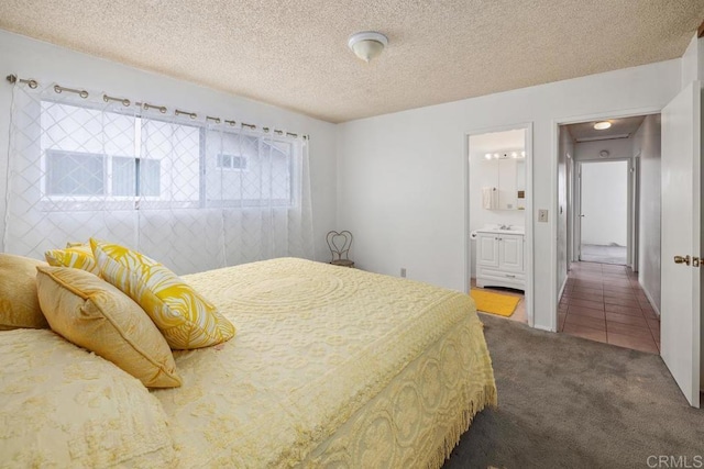 carpeted bedroom featuring a textured ceiling and connected bathroom