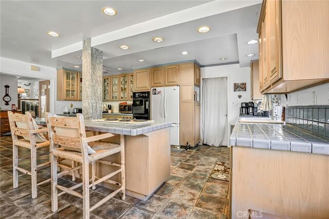 9522 Yellowstone Dr, Huntington Beach, CA 92646 - kitchen featuring tile counters, freestanding refrigerator, a kitchen breakfast bar, recessed lighting, and glass insert cabinets