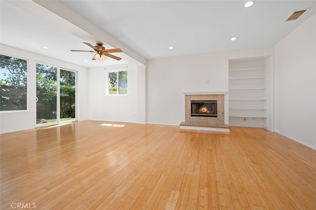 8542 E Heatherview Ln, Orange, CA 92869 - unfurnished living room with light wood finished floors, a tiled fireplace, a ceiling fan, recessed lighting, and built in features